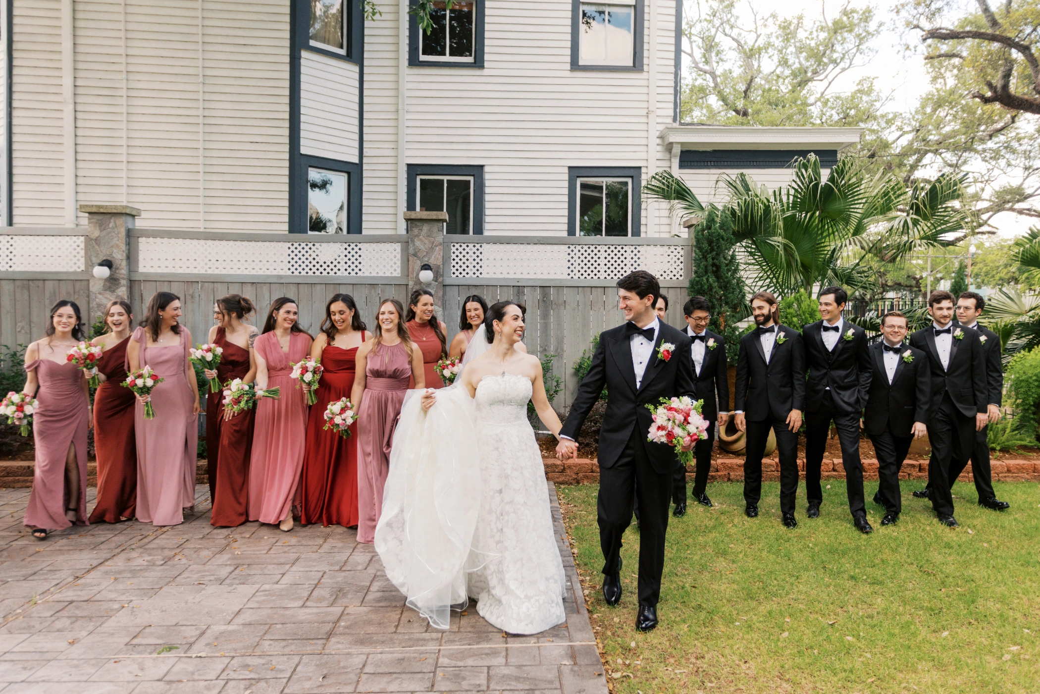 Paulina and Michael leading their whole wedding party across the Canal St Inn courtyard, bridesmaids in pink and groomsmen in tuxedos