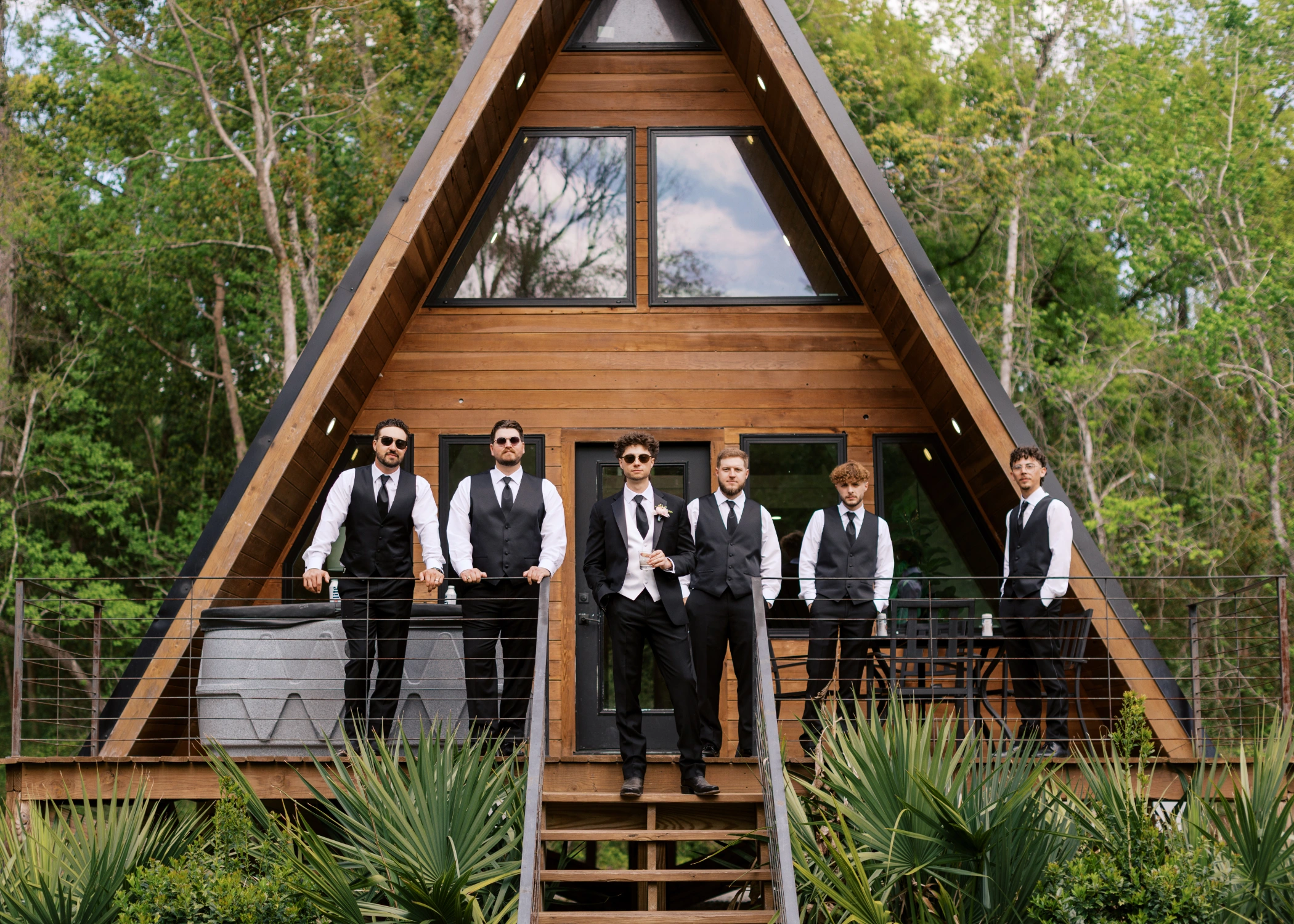 Zane and his groomsmen in black vests and sunglasses on the porch of the modern A-frame house in New Iberia