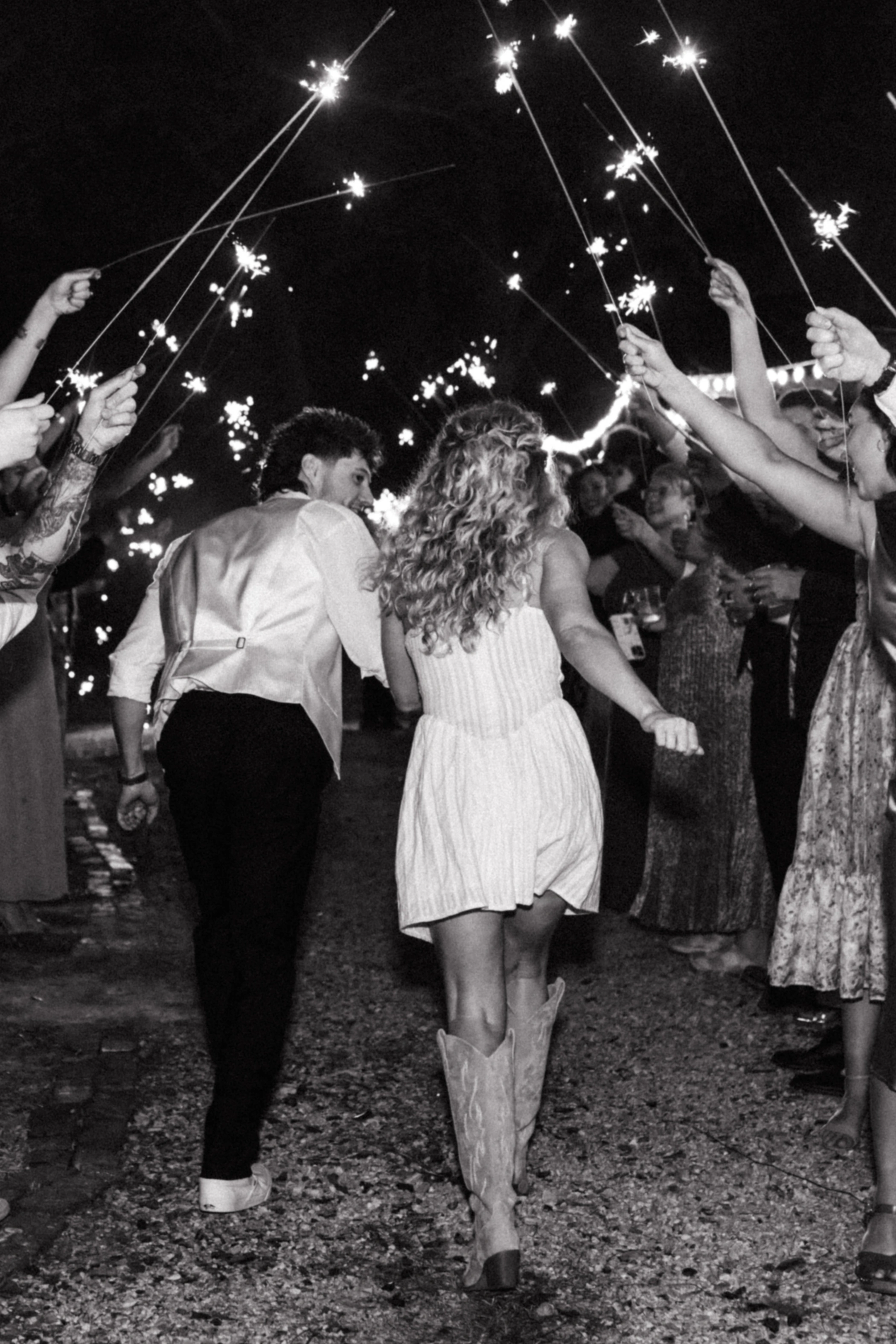 Taylor and Zane running through a tunnel of sparklers held by friends and family to end the night
